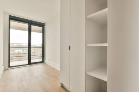 Spacious dressing room with a large white wardrobe and access to the balcony